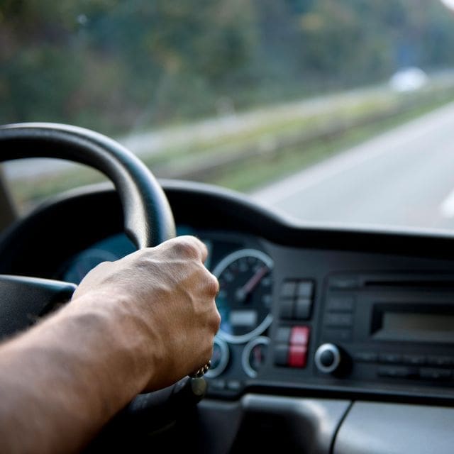 a hand on the steering wheel of a car