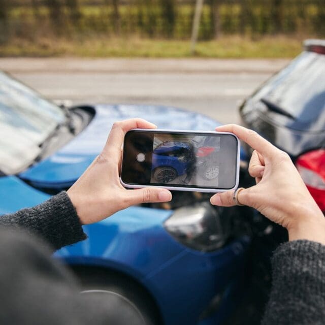 a person holding a phone to take a picture of a car