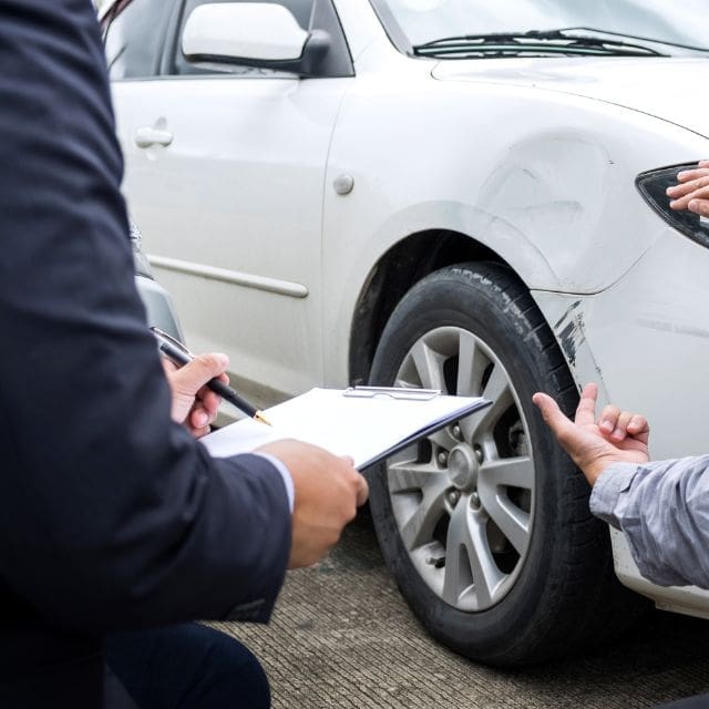 two men inspecting a damaged car